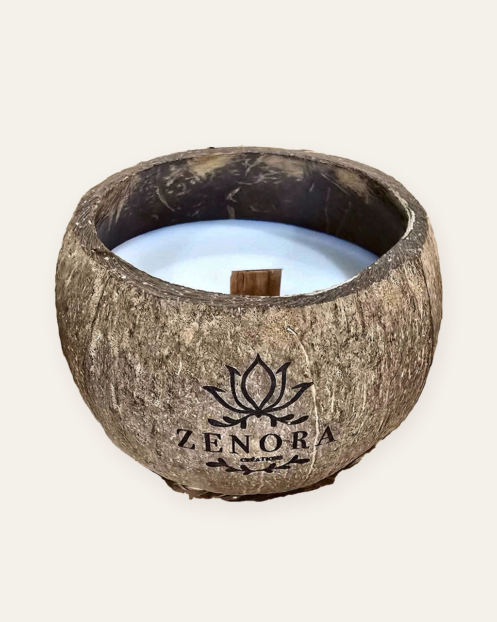 Bougie Zenora dans une coque de noix de coco, sur fond clair