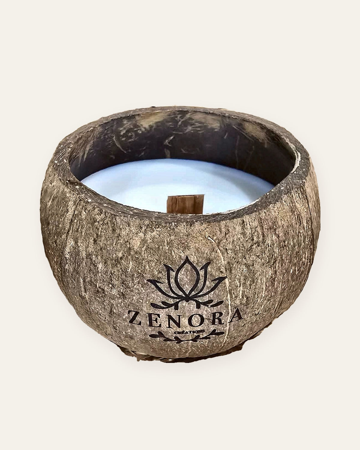 Bougie Zenora dans une coque de noix de coco, sur fond clair